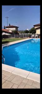 een groot blauw zwembad met twee stoelen erin bij Appartamento Polpenazze - Relax in collina con piscina in Polpenazze del Garda +2 foto's