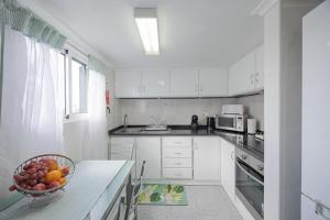 a white kitchen with a bowl of fruit on a counter at Peaceful Panorama by YOUR KEY MADEIRA in Porto Moniz