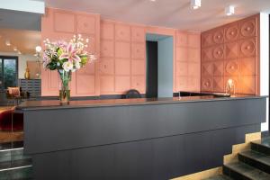 a lobby with a counter with a vase of flowers at Hôtel Pax in Geneva