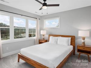 a white bedroom with a bed and two windows at French Broad Overlook in Asheville