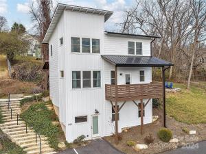 a white house with a balcony on top of it at French Broad Overlook in Asheville