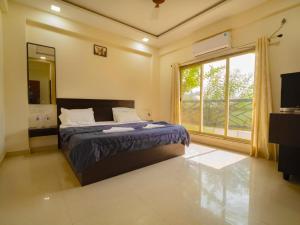 a bedroom with a bed and a large window at Beach Aura By Lavika Stays in Nagaon