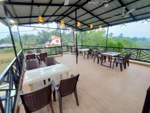 a restaurant with tables and chairs on a balcony at Beach Aura By Lavika Stays in Nagaon