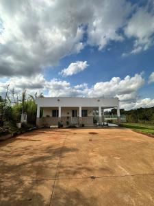 a large white building on a dirt road at Sítio Vista Azul - Lazer e descanso na natureza in Mateus Leme