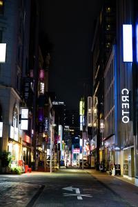 Una calle vacía de la ciudad por la noche con edificios iluminados en Hi Seoul Hostel West, en Seúl