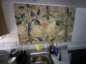 ThorpeBrightOwl Waterside Narrowboat Cottage Experience的厨房水槽上方挂着一幅挂毯