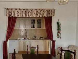 cocina con cortinas rojas y mesa en una habitación en Small Hill Guesthouse, en Podgorica