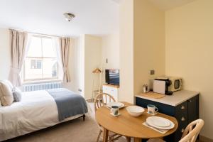 a bedroom with a bed and a table with a tv at Delabere House - Luxury Cotswolds Holiday Apartments in Moreton in Marsh