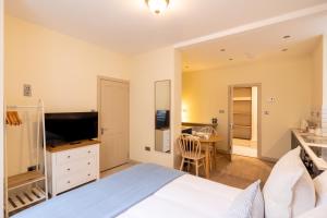 a bedroom with a bed and a desk with a television at Delabere House - Luxury Cotswolds Holiday Apartments in Moreton in Marsh