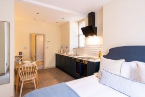 a bedroom with a king sized bed and a kitchen at Delabere House - Luxury Cotswolds Holiday Apartments in Moreton in Marsh
