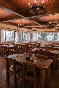 ein Restaurant mit Holztischen und -stühlen und Fenstern in der Unterkunft Hosteria de la Villa - Moonski in San Carlos de Bariloche