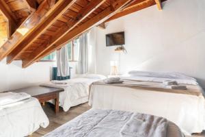 2 Betten in einem Zimmer mit weißen Wänden und Holzdecken in der Unterkunft Hosteria de la Villa - Moonski in San Carlos de Bariloche