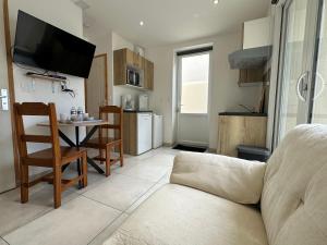 een woonkamer met een bank en een tafel en een keuken bij Chez Camille & Emma - Climatisé in Rochefort