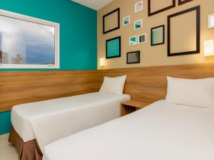 two beds in a room with blue walls at Golden Tower Express Braz Olaia by Fênix Hotéis in Ribeirão Preto