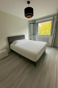 Cama blanca grande en habitación con suelo de madera en Grand appartement 2 chambres lumineux et moderne à Honfleur, en Honfleur