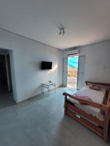 een slaapkamer met een bed en een flatscreen-tv bij Chalé do João in Ubatuba