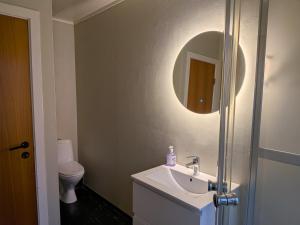 een badkamer met een wastafel en een spiegel en een toilet bij Aurora Seaview Escape E33 in Slåttvikstrand