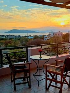 a balcony with a table and chairs and a sunset at The house of joy in Egina