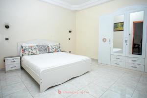 Cabral residence في Guediawaye: غرفة نوم بيضاء مع سرير وخزانة