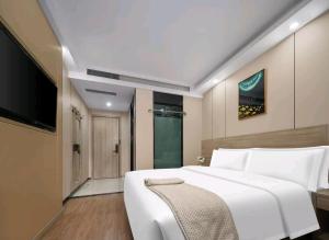 a bedroom with a large white bed and a flat screen tv at Jiaming Hotel in Yingwanzhen