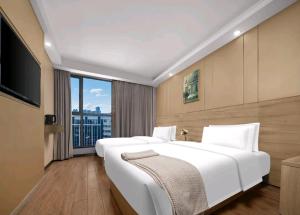 a bedroom with two white beds and a large window at Jiaming Hotel in Yingwanzhen