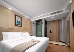 a bedroom with a large white bed and a glass door at Jiaming Hotel in Yingwanzhen