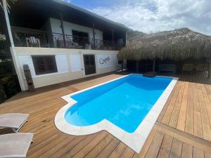 a resort with a blue swimming pool on a wooden deck at Vue imprenable sur la mer des Caraïbes in Les Anses-dʼArlets