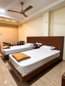 a bedroom with two beds and a ceiling fan at Shri Amman Residency in Dhārāpuram