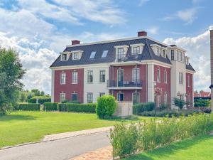 a large red and white house with a yard at SeaLuxe Suite 27i in Colijnsplaat