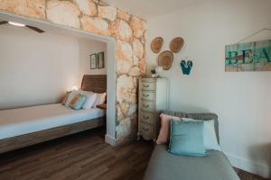 Un dormitorio con una cama y una pared de piedra. en Guana Beach Inn, en Great Guana Cay