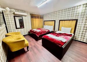 イスラマバードにあるFrank-inn Guest House Islamabadのベッド2台と椅子が置かれた寝室