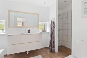 een witte badkamer met een wastafel en een spiegel bij 823-Tisvildeleje-Vibevaenget-13-A in Tisvilde +12 foto's