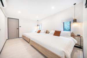 a large white bedroom with two large beds at The Mellow at Ekkamai in Bangkok