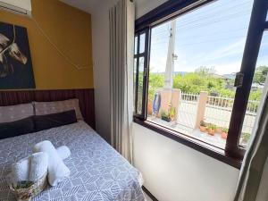 a small bedroom with a bed and a window at Hospedagem com café da manhã - Quarto 1 - Hospedaria Orquídeas de Bombinhas in Bombinhas