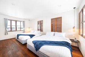 two beds in a room with white walls and windows at The Mellow at Ekkamai in Bangkok