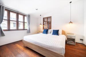 a bedroom with a large white bed with blue pillows at The Mellow at Ekkamai in Bangkok
