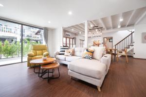 a living room with a white couch and chairs at The Mellow at Ekkamai in Bangkok
