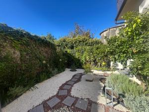 ETNA HOUSE LUXURY con giardino e vasca idromassaggio في لينغواغلوسا: حديقة بها ممر وكرسي ونباتات