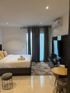 a bedroom with a bed and a tv and a table at Bloom Styled Studio at The Lennox in Accra +14 photos