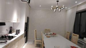 een keuken met een witte tafel en een kroonluchter bij Voyage in Karakol