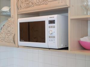 a white microwave in a cabinet in a kitchen at Kyiv Sky Apartment in Kyiv