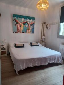 a bedroom with a large white bed and a chandelier at Maison de la Plage in Soulac-sur-Mer
