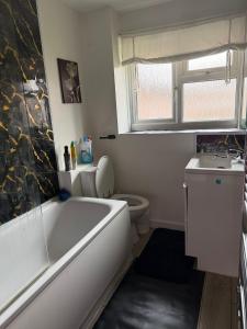a bathroom with a tub and a toilet and a sink at COSY Rooms in Grove Park +9 photos