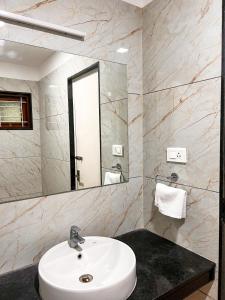 a bathroom with a white sink and a mirror at Shri Amman Residency in Dhārāpuram +21 photos