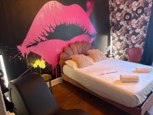 a bedroom with a bed with a pink face on the wall at La Parisienne Coquine Love and Plaisir - Love Room in Troyes