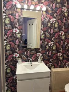 a bathroom with a sink and a flower wallpaper at La Parisienne Coquine Love and Plaisir - Love Room in Troyes +16 photos