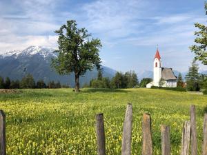 een kerk in het midden van een veld met een hek bij Vista Apartments in Seefeld in Tirol