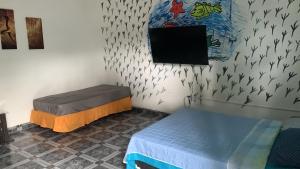 ポルトベロにあるVilla Bellaのベッドが2つと壁にテレビがある部屋