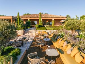 a patio with tables and chairs in a garden at La Bastide Saint Georges & Spa in Forcalquier