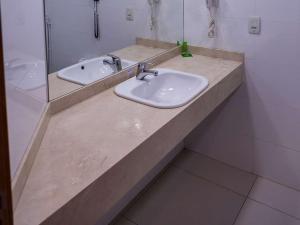 a bathroom with a counter with two sinks and a mirror at Golden Tower Maurilio Biagi by Fênix Hotéis in Ribeirão Preto +8 photos